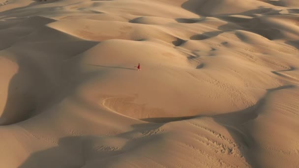 4K slow motion widok z lotu ptaka kobieta spaceruje przez wydmy na dzikiej pustyni przyrody — Wideo stockowe