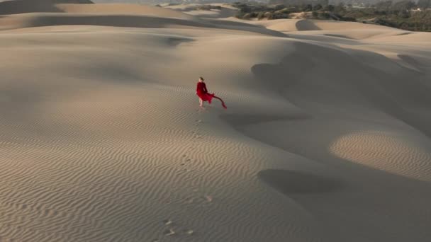 4K vue aérienne de la femme marchant par les dunes de sable dans la nature désertique