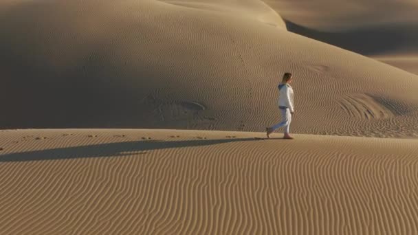 4K slow motion antenn av kvinna promenader genom sanddyner med vackra vågiga mönster — Stockvideo