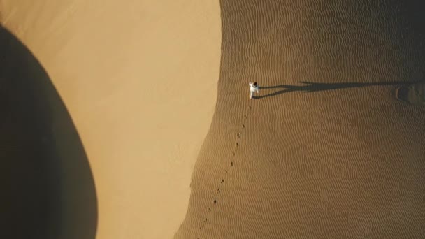 Vista aérea 4K de la mujer caminando por dunas de arena en la naturaleza del desierto — Vídeos de Stock