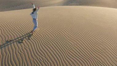 Kum tepeciğinde koşan kadının 4K yavaş çekim hava görüntüsü, ABD çöl doğası.