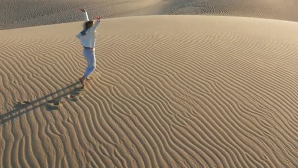 Kum tepeciğinde koşan kadının 4K yavaş çekim hava görüntüsü, ABD çöl doğası. — Stok video