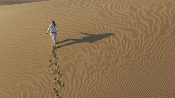 4K slow motion vue aérienne de la femme grimpant au sommet de la dune de sable, USA nature