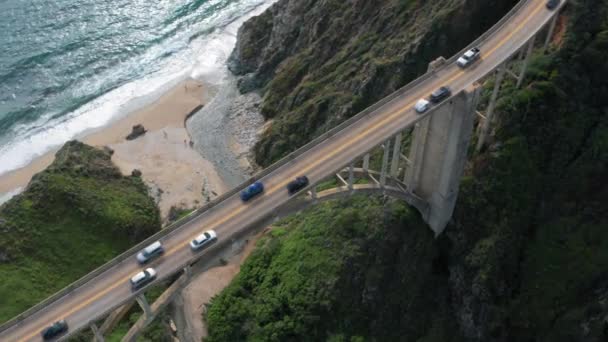 Tráfico por el puente del arco que tiene una ubicación increíble en la costa del océano. Imágenes aéreas . — Vídeos de Stock