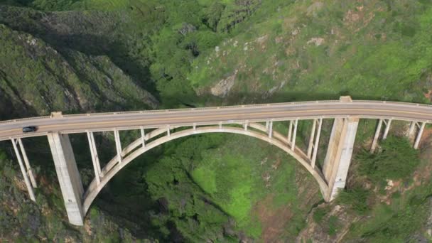 Tráfico por el puente del arco que tiene una ubicación increíble en la costa del océano. Imágenes aéreas . — Vídeos de Stock