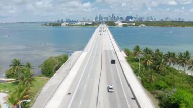 Florida 'da yaz güneşli bir günde Miami Körfezi üzerindeki karayolu köprüsünde 4K hava manzarası