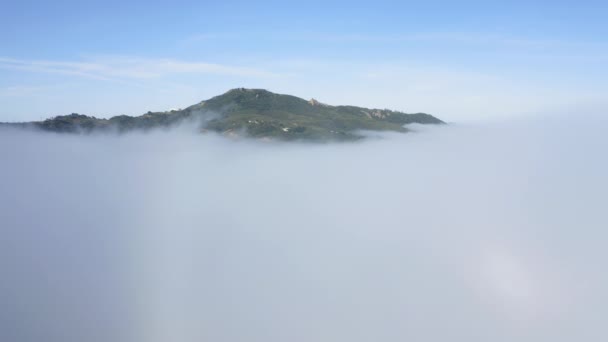 Вид с воздуха на зеленую гору, покрытую густыми туманными облаками на восходе солнца. Малибу, США — стоковое видео