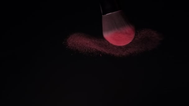 メイクブラシは、黒を背景にピンクの赤面粉を広げています。スローモーション — ストック動画