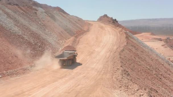 Bir çöp kamyonu kırmızı taş ocağının yanından geçiyor. Arkasında toz bulutu var. — Stok video