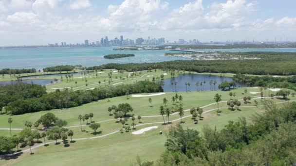 4k εναέρια άποψη του πράσινου γηπέδου γκολφ με Μαϊάμι στο κέντρο της πόλης σε φόντο, Φλόριντα — Αρχείο Βίντεο