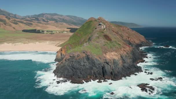 風光明媚な緑の岩の島、夏の4K上の灯台のシネマティックな空中ビュー — ストック動画