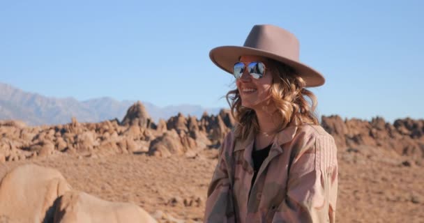 Felice donna sorridente in cappello sta godendo di un'alba soleggiata nella natura della valle rocciosa. — Video Stock