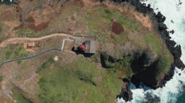 Yeşil kayalık adada kırmızı çatılı deniz feneri manzaralı, 4K