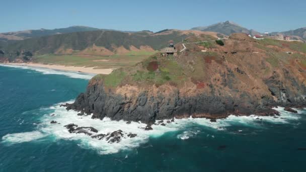 Vista aérea cinematográfica de um farol em uma ilha rochosa verde cênica, verão 4K — Vídeo de Stock