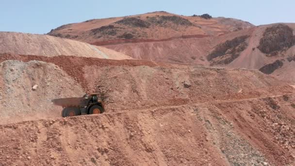 Dumper trucks rijden door schilderachtige rode steengroeve met stof wervelend achter — Stockvideo