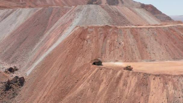 Aeronave cinematográfica de um caminhão-ponta descarregando a areia vermelha e pedras na pedreira — Vídeo de Stock