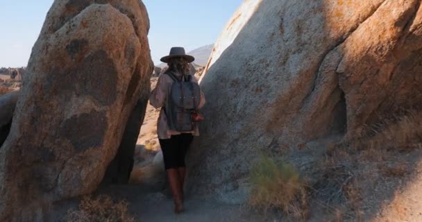 Mladá usměvavá žena s batohem je turistika v malebném skalnatém kaňonu při východu slunce — Stock video