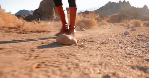 Gros plan de femmes indépendantes en bottes rouges randonnée route désertique poussiéreuse au lever du soleil — Video