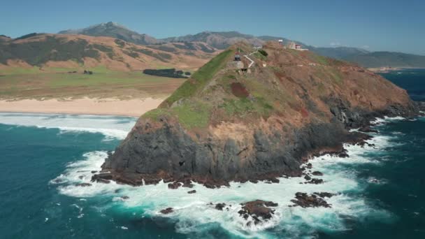 風光明媚な緑の岩の島、夏の4K上の灯台のシネマティックな空中ビュー — ストック動画