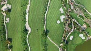 Golf sahası 4K yukarıdan aşağıya doğru. Yeşil golf sahasındaki insanlar spor oyunu oynuyorlar