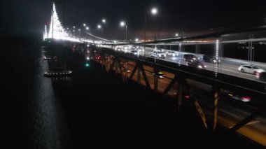 Kablo köprüsünün destansı gece çekimi karanlıkta beyaz ışıklarla aydınlatılmış, 4K 