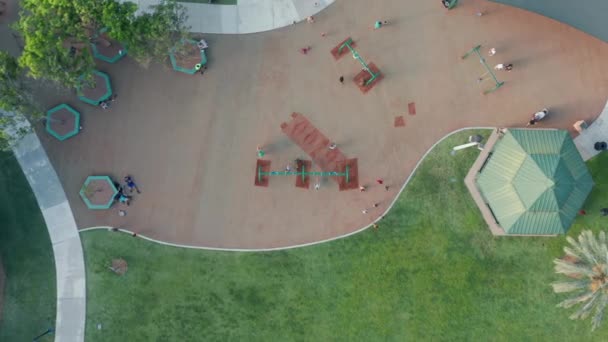 ครอบครัวที่มีเด็กในพื้นที่สนามเด็กเล่นในสวนสาธารณะสีเขียวไมอามี่ในฤดูร้อน — วีดีโอสต็อก