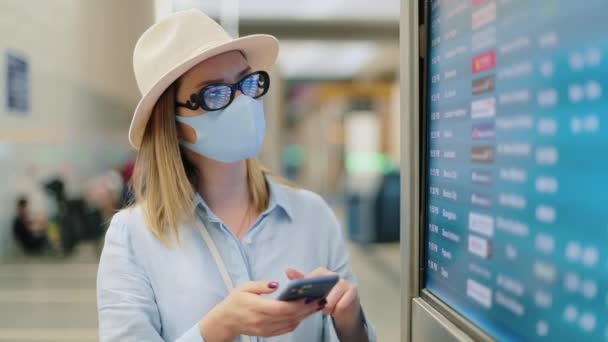Путешественник случайный наряд и маска для лица поиск рейса по расписанию в аэропорту — стоковое видео