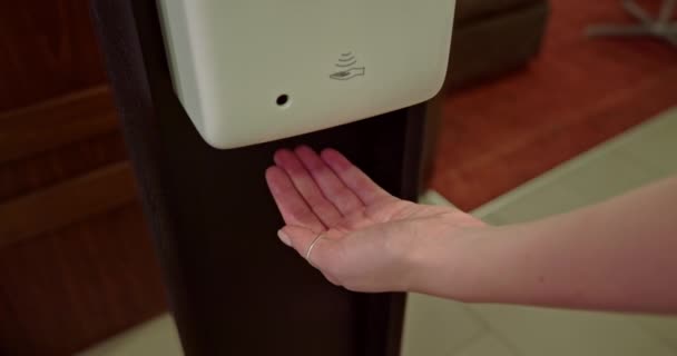 Cerca de la mano de la mujer en la estación de gel de desinfección. Mujer usando gel antibacteriano — Vídeos de Stock