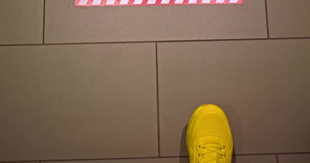 Hombre en zapatos deportivos está caminando en el vestíbulo del hotel por COVID-19 señalización de prevención 4K — Vídeo de stock