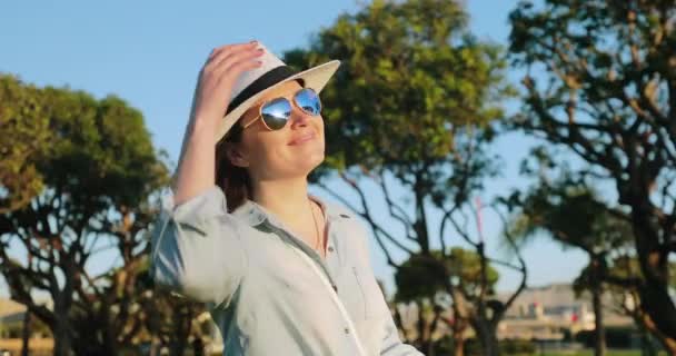 Bastante joven hembra en sombrero blanco disfrutando de la hermosa puesta del sol y el viento soplando, 4K — Vídeos de Stock