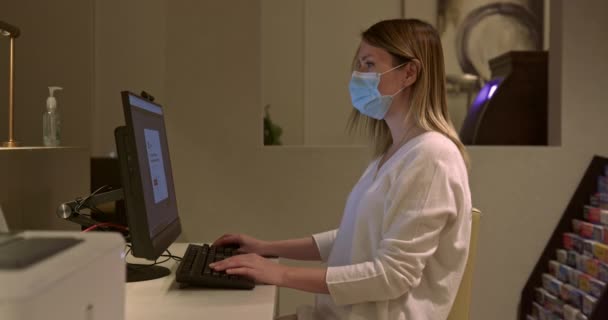 Vista lateral de la mujer confiada en la máscara facial que trabaja en la computadora en la oficina de negocios — Vídeos de Stock