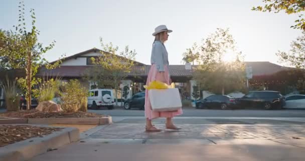 4K lassított felvétel vásárlás. Független nő sétál bevásárlószatyrokkal naplementekor — Stock videók