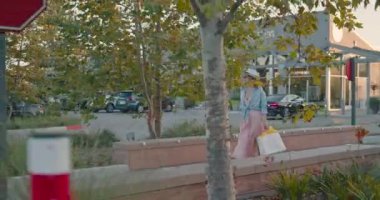 Ağır çekimde alışveriş. Kamera zarif, pembe elbiseli bir kadının etrafında dönüyor, 4K