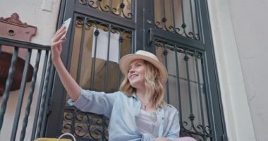 Çekici genç bayan telefonda selfie çekerken gülümsüyor. Şık gezgin