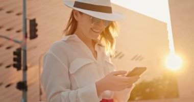 Sarı saçlı, gülümseyen bir kadın telefona bakıyor ve gülümsüyor, 4K