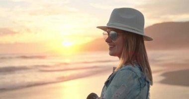 Güzel gülüşlü hoş bir kadın pembe ve şeftali rengi günbatımı manzarasının tadını çıkarıyor, Malibu