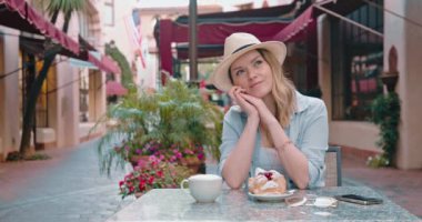 Güzel bir kadın Avrupa 'nın eski tarihi kasabasındaki sokak restoranında hayal kuruyor.