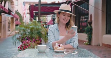 Güzel gezgin eski Avrupa şehrinin caddesindeki fırında kahvenin keyfini çıkarıyor, 4K