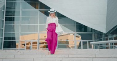 Şehirde alışveriş torbalarıyla gezen şık giysili bir kadın. Ağır çekim moda