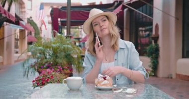 Çekici kadın, Avrupa 'daki küçük kafede akıllı telefonla arkadaşıyla konuşuyor.