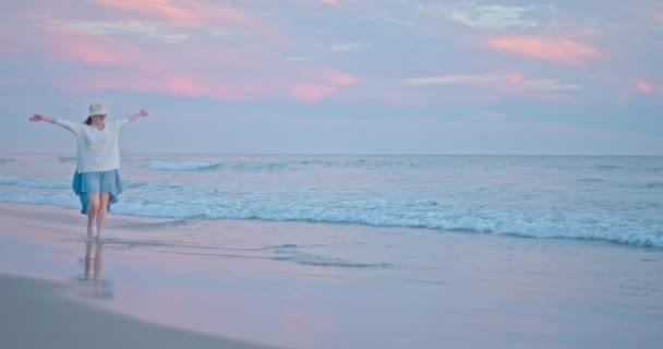 Веселая красивая женщина танцует на пляже и чувствует счастье на закате — стоковое видео