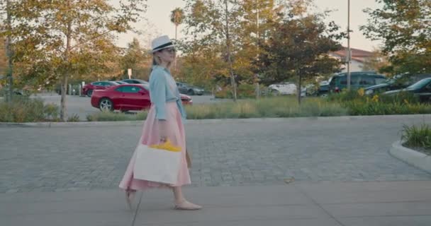 Kobieta z torbami spaceru ulicą parking w centrum handlowym w letni wieczór — Wideo stockowe