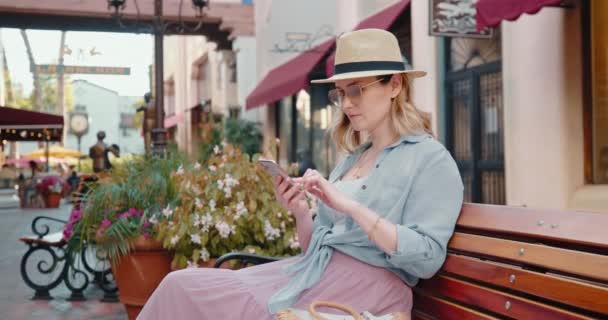 Pretty model is reviewing mail on her smartphone. 4K slow motion Europe vacation — Stock Video