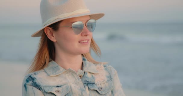 Спокійна і розслаблена жінка дивиться на захід сонця на пляжі і насолоджується природою — стокове відео