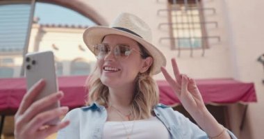 Çekici kadın portresi beyaz akıllı telefonda selfie çekerken gülümsüyor.