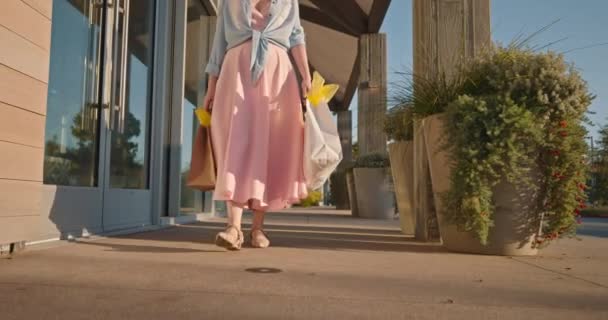 Woman in pink dress with paper bags walking by shopping mall. 4K slow motion — Stock Video