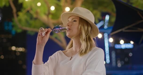 Bella donna si sta godendo un drink in flauto durante la festa notturna nel parco verde. 4K — Video Stock