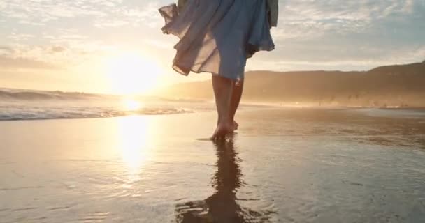 Mujer de cámara lenta caminando descalza en olas oceánicas con luz dorada al atardecer. 4K — Vídeo de stock