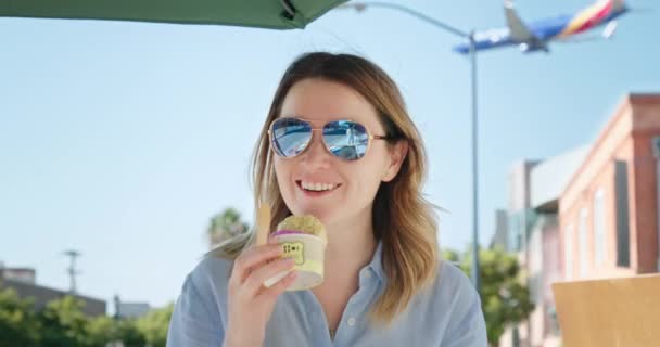 Chica sonriente disfrutando de sabroso helado en un cono de gofre, avión sobre fondo — Vídeo de stock