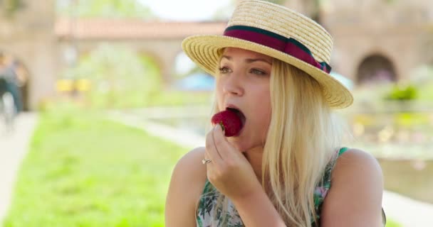 Sexy young woman eats strawberry fruit in green park. 4K woman slow motion — Stock Video